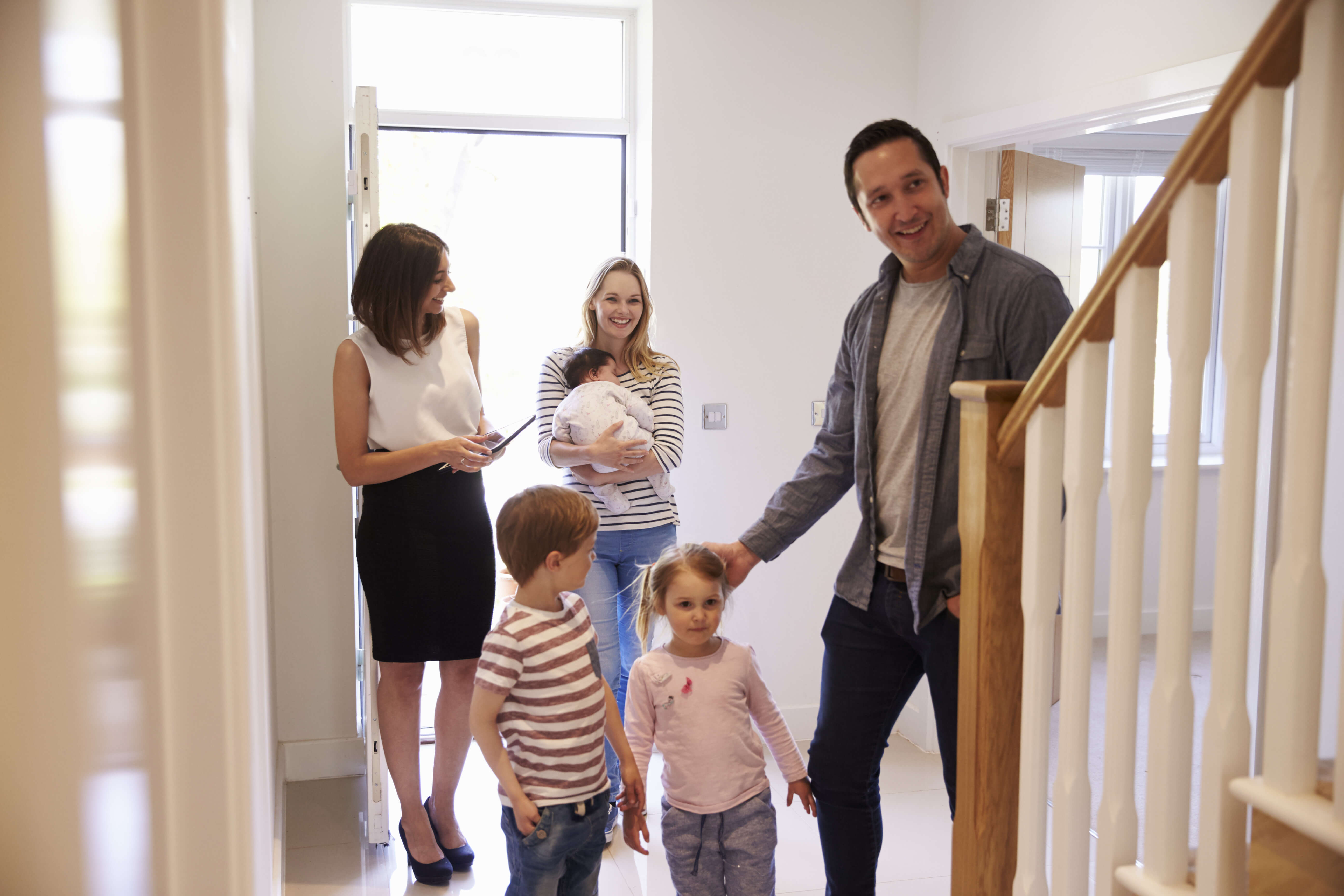 Courtier immobilier fait visiter une maison à vendre par une jeune famille d'acheteurs.